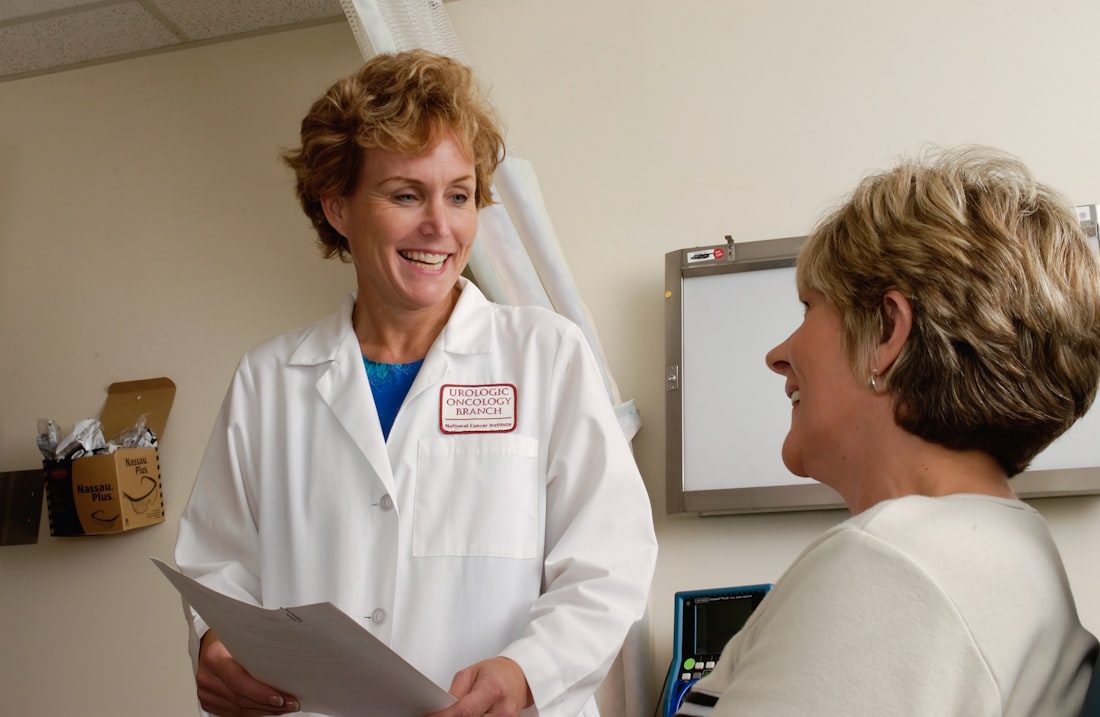 A clinician and a patient in conversation during a consultation, both smiling.